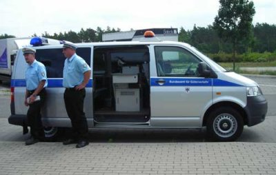 Photo of enforcement officers standing beside a mobile enforcement vehicle for the Toll Collect system in Germany.