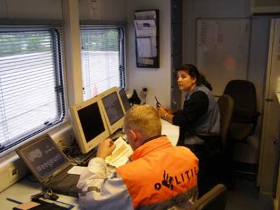 Photo of two enforcement officers sitting at laptop computers in the interior of a mobile enforcement unit in the Netherlands.