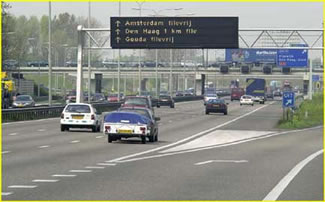 Photo of dynamic route information panel over roadway showing information on queuing and travel time changes due to congestion.