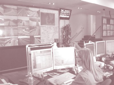 Photo of interior of the Traffic Information Center in Copenhagen, Denmark, with a woman sitting in front of computer monitors and additional monitors on a wall.