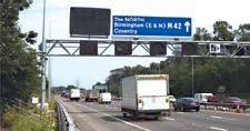 Photo of vehicles traveling on the M42 ATM under normal motorway conditions. Variable message signs on the overhead gantry are blank.