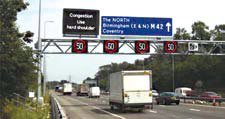 Photo of vehicles traveling on the M42 ATM with hard shoulder running. Variable message sign over shoulder lane reads 'congestion, use hard shoulder.' Signs over all lanes indicate a speed of 50.