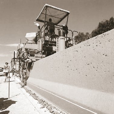 Photo of slipform paving of the safety barriers on the E40-A10 CRC overlay project.