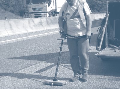 Photo of worker taking layer thickness measurements on a roadway section.