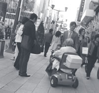 Photo of an elderly shopper using a mobility scooter on a Tokyo sidewalk.