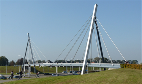 Figure 27 Segregation of the road network and the cycle network - Description: A bridge in the Netherlands that has cars driving under it and a side road beside it, separated by grass, for cyclists 