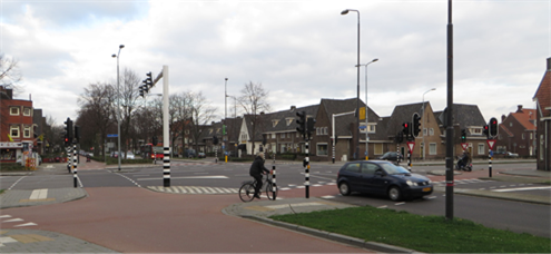 Figure 30 Example of an intersection in Utrecht - Description: An four way intersection with black and white marked poles and houses surronding it.