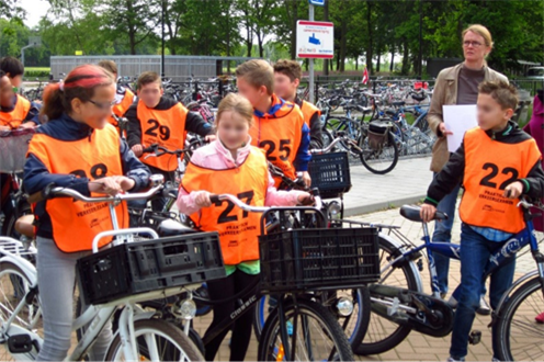 Figure 32 Traffic exam in Deventer - Description: A group of kids with orange vests getting on their bikes 