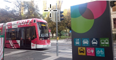 A transit bus stop with a sign indicating the availability of car-charging stations, bus and rail transfers, carpooling, and bikeshare.