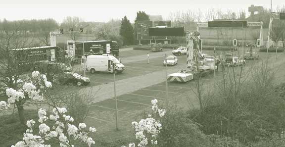 Pictured is a paved surface containing a variety of consumer, commercial, and support vehicles, traffic signals, static and electronic signage systems, a truck mounted attenuator and other safety systems.