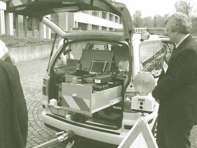 A closer view of the rear of the ADAC van, showing the vehicle's tow bar in place, equipment drawer open, and diagnostic computer opened and ready to use.