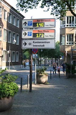 Photo of real-time parking information display in Cologne showing numbers of available spaces at nearby parking lots.