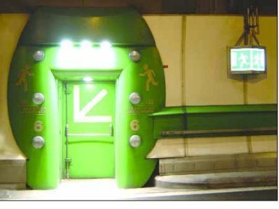 A door inside the Mont blanc tunnel. The door is painted green with yellow arrows and running figures in the direction of the door handle. The green paint continues around the door to make it more visible, then extends in a horizontal wide stripe along the tunnel wall at about waist level.