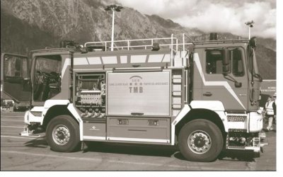 Photograph of a Mont Blanc Tunnel fire truck with mountains in the background. It's relatively short in length and has driver controls at both ends with all necessary equipment located between the two.