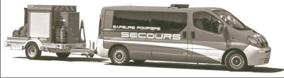 An elongated van with the words Sapeurs Pompiers Secours on the side, pulling a trailer with safety and fire fighting equipment.