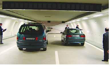 Photograph of the interior tunnel model. Two cars are shown driving away from us; one in each lane. There are a four people standing about, showing this is a full scale model.